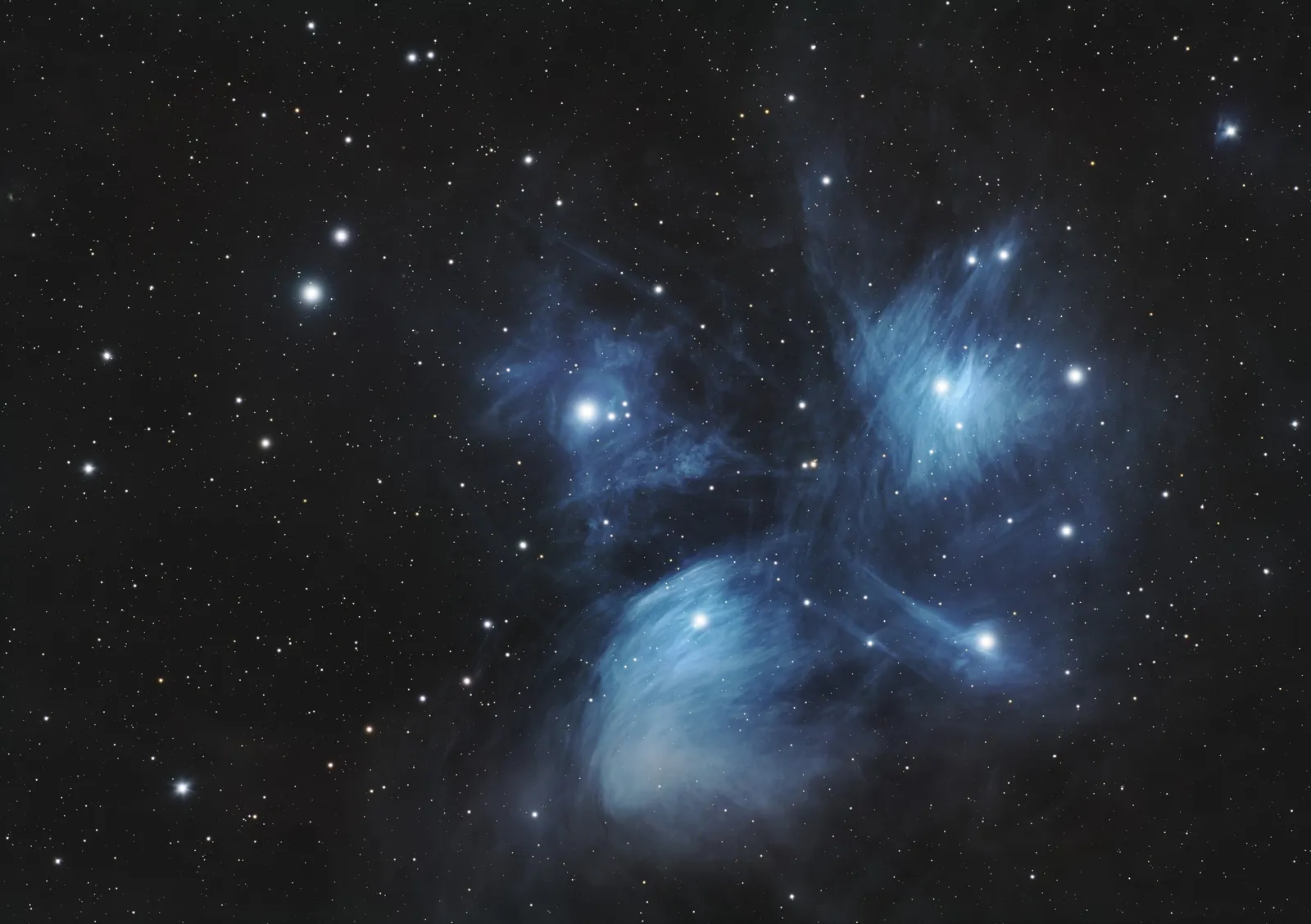 The Pleiades star cluster (M45) wrapped in wisps of blue reflection nebulosity