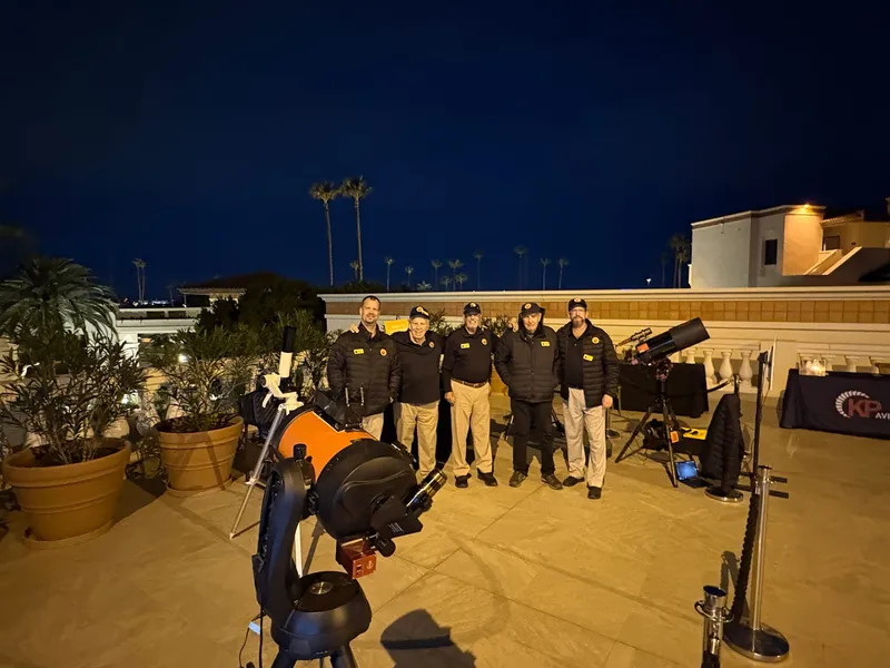 Five PAS operators with telescopes at a rooftop resort event at night